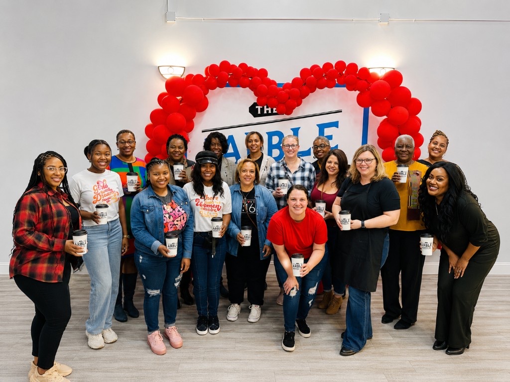 A group of guests gathered beneath a red heart balloon display at Arble Baking Company