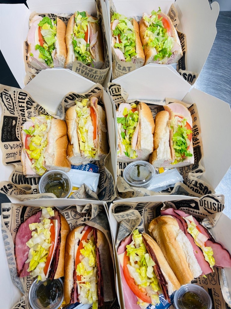 Arble boxed lunches filled with deli sandwiches, lettuce, tomato, and pickles