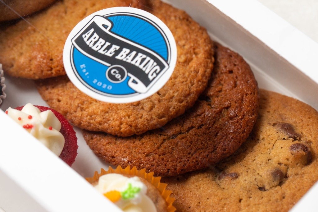 An Arble Baking Company box filled with assorted cookies and mini desserts