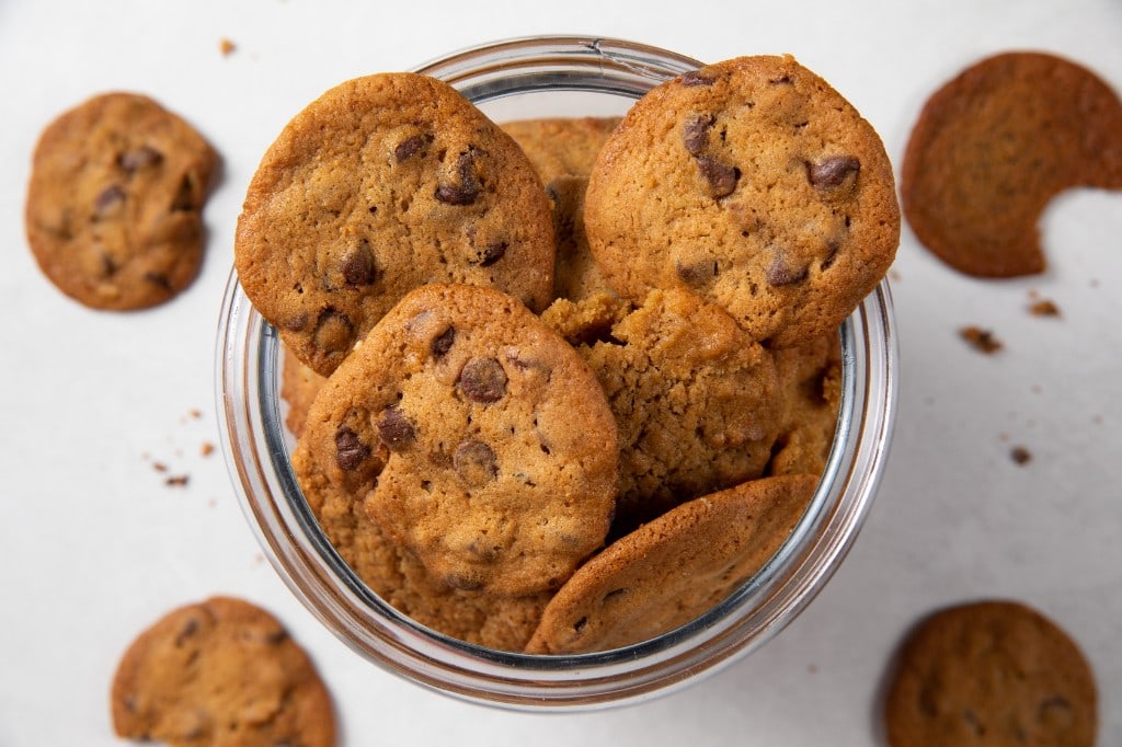 Fresh-baked Arble cookies arranged in and around a glass bakery jar