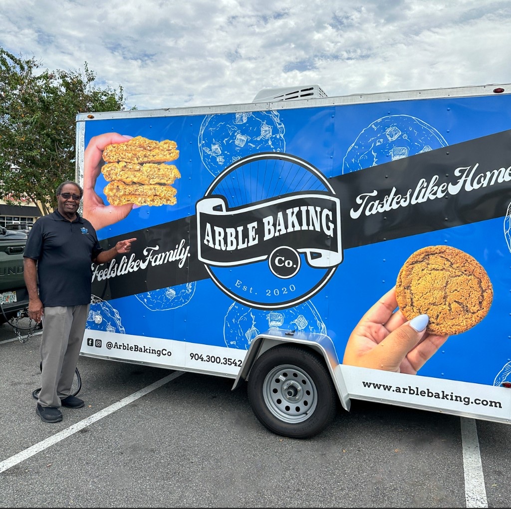 Willis Anderson standing beside the blue Arble Baking Company food truck