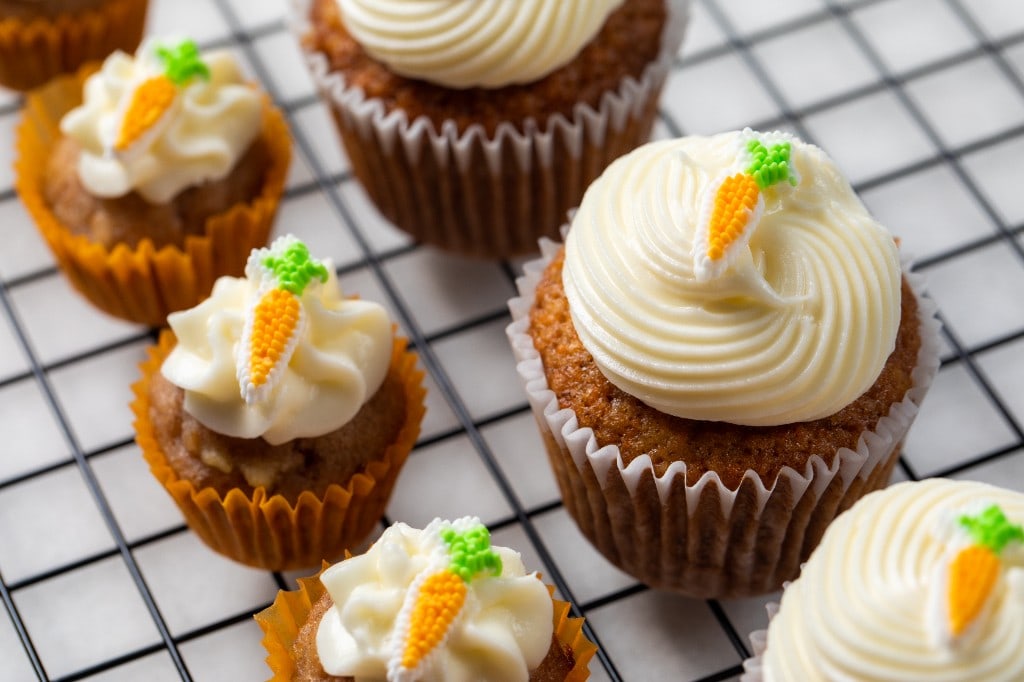 Full-size and mini carrot cupcakes with cream cheese frosting and small carrot decorations