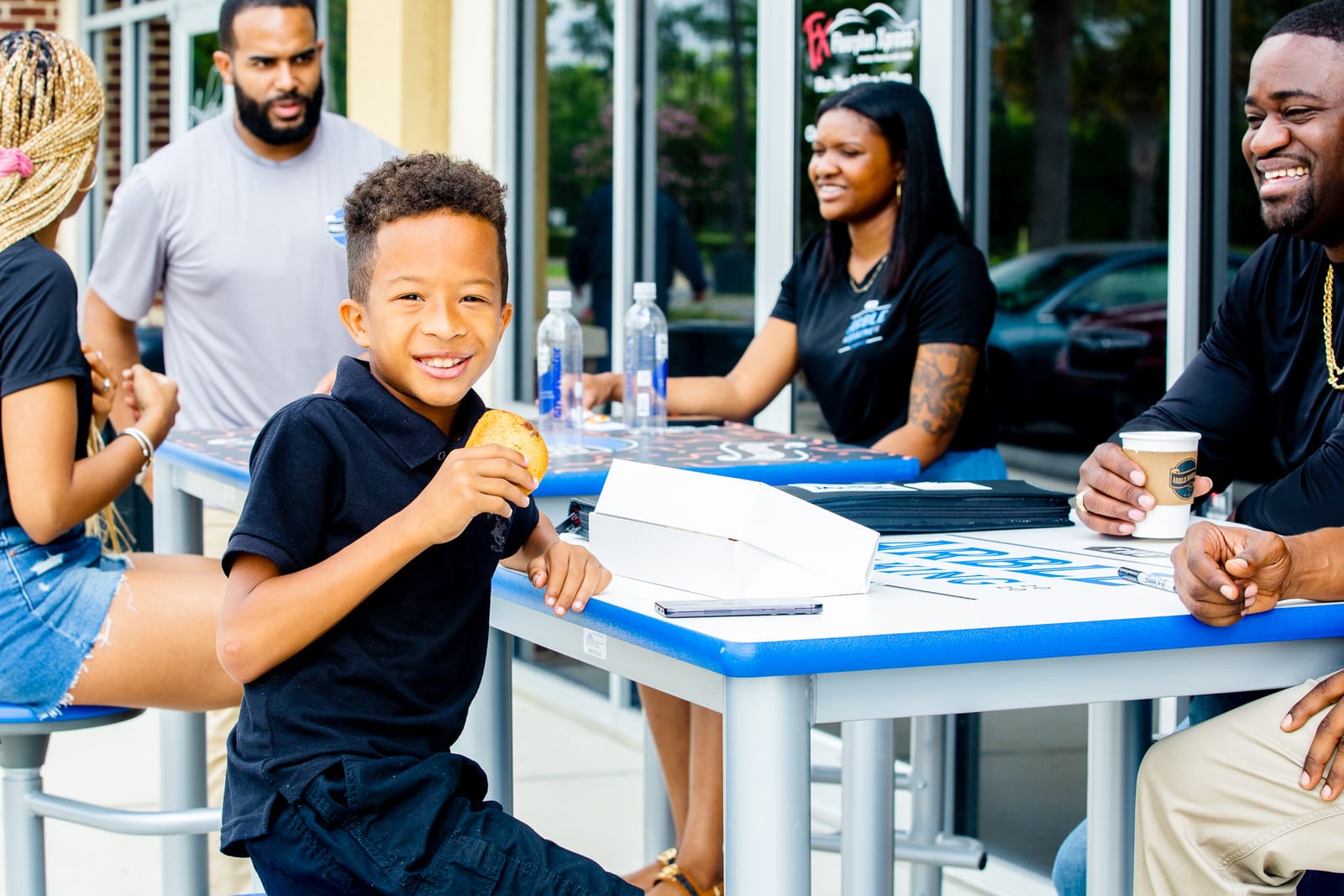 A young guest enjoying an Arble cookie with family outside the bakery